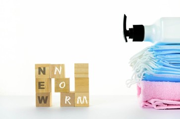 Conceptual new normal due to Covid-19. Wooden block stacked to form N with texts besides ace masks and  hand sanitizer. Selective focus on wooden cubes.