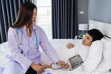 Obraz premium doctor measuring blood pressure of sick man in bed