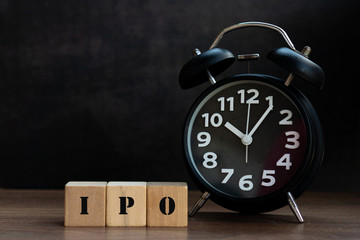 IPO text on wood block with clock, conceptual