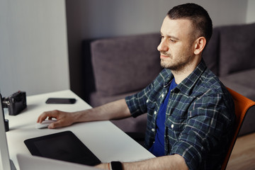 Handsome freelancer man working remotely from home. Young male working on his computer