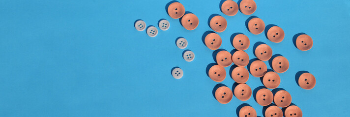  On a blue background a scattering of coral buttons. Needlework. Accessories for sewing. Copy space. Banner. 