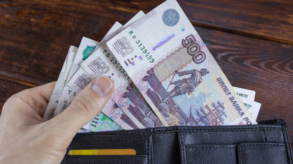 The lot with Russian rubles is pulled out by hand from the wallet with credit cards.Paper banknotes...