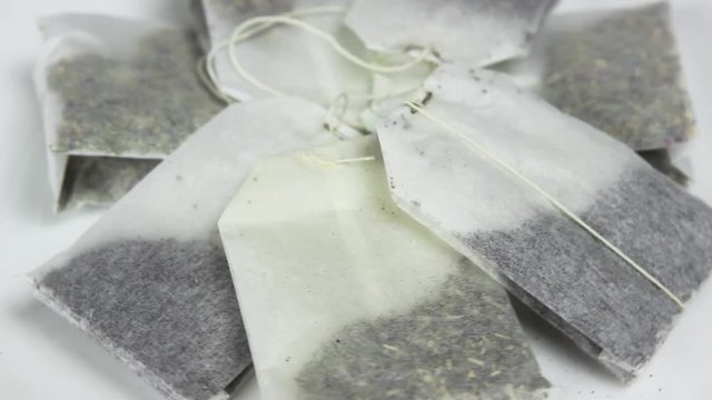 Tea bags with different sorts of tea rotate on a white porcelain plate