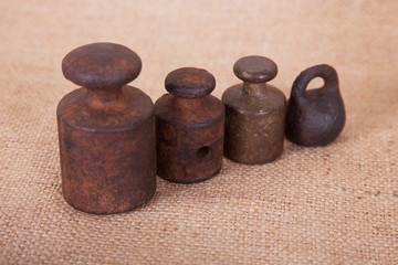 Old kettlebell weight measures on a background of burlap.