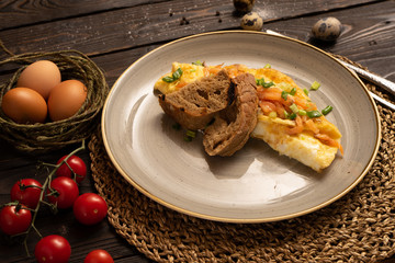 Omelet with salmon, green onions and bread is beautifully served on a dark wooden table. Food close-up.