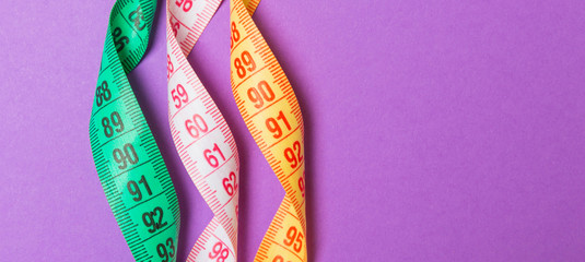 Close up of colorful measure tapes on purple background. Perfect female figure measurements concept