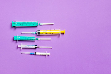 Top view of different syringes at purple background. Medical injection concept with copy space