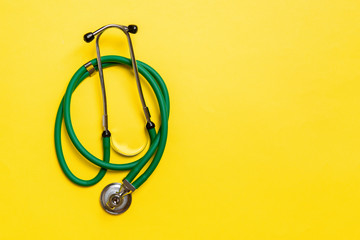 Top view of green medical stethoscope on colorful background with copy space. Medicine equipment...