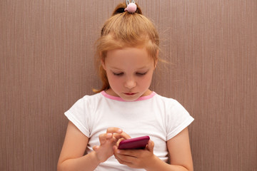 red-haired girl child uses a smartphone