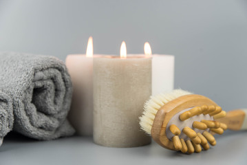 Fototapeta na wymiar Towel with aromatic candles and massage brush. Aromatherapy and beauty. Concept set of harmony, balance and meditation, spa, relax, beauty spa treatment.