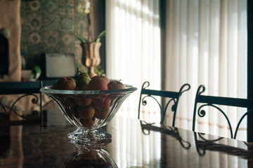 
apples in a large crystal vase. A large glass dish with apples stands on the table. A crystal vase with apples stands on a large table on the vernada on a sunny day