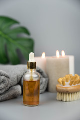 Obraz na płótnie Canvas Towel with aromatic candles, bottle with natural organic essential oils and massage brush. Aromatherapy and beauty. Concept set of harmony, balance and meditation, spa, relax, beauty spa treatment.