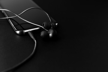 Black Headphones and Mobile phone on a black background