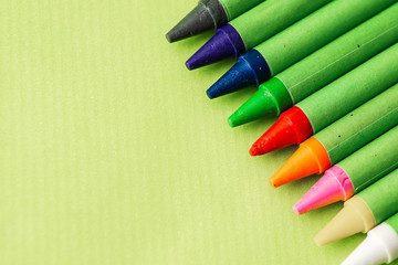 colored wax pencils on a green background