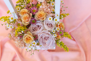 Delicate flower arrangement in a wooden box with a pen on a pink background (Colors: yellow, pink, white, pink, vanilla. Flowers: rose, carnation, solidaga, chrysanthemum)