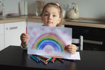 Girl painting rainbow at home, a symbol of UK National Health Service (NHS). Thanks to the doctors for their work. Stay at home Social media campaign.