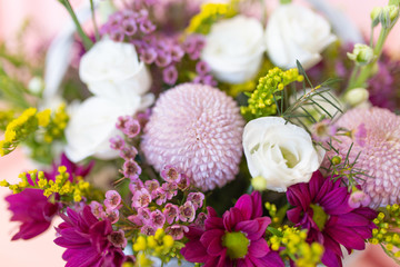 An emotional bouquet of fresh flowers in a white wicker basket on a light background (Colors: white, pink, yellow, purple, lilac. Flowers: eustoma, chrysanthemum, chamelacium, solidaga)