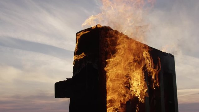 In the frame, a piano burning with bright flames against the blue sky and sunset. I set the piano on fire. The fire from the piano. An artistic production. The art scene.