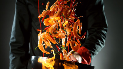 Closeup of chef throwing prawns from wok
