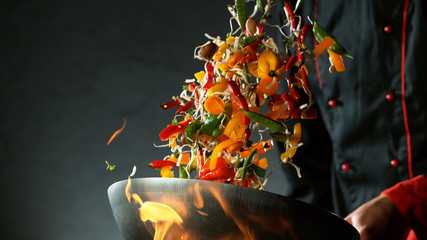 Closeup of chef throwing vegetable mix from wok