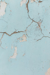 Texture of cracked wall with light blue paint, background or backdrop of abandoned building exterior.