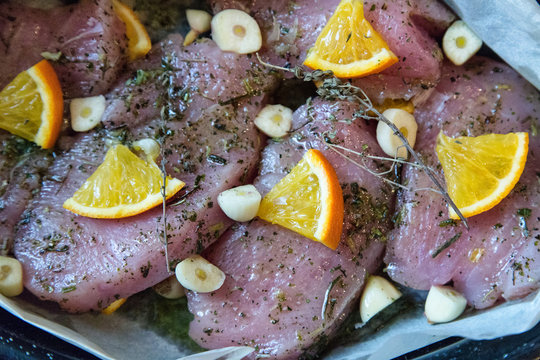Raw chicken (turkey) fillet covered with garlic, herbs and orange slices in oven tray prepared for roasting. Homemade cooking.