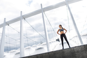 Full length a young confident girl in excellent physical shape standing outdoors, wearing sports clothes and sneakers. The concept of outdoor sports training, healthy lifestyle