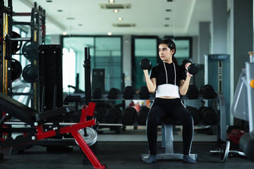 Fototapeta na wymiar Young beautiful girl doing exercises with dumbbell in gym.