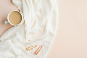 Cup of coffee with white blanket on beige background. Flat lay, top view. Cozy home desk, autumn fall, hygge style concept.