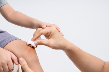 Mother hand holding cotton wool soaked with Povidone iodine for do basic first to the wound on her...