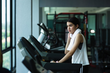 Side view of beautiful girl running on treadmill at gym