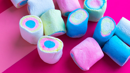 Scattered multi-colored marshmallows on a pink background. Holiday treat. Sweet gift. Children's holiday. Use for postcards. The horizontal location. Selective focus.
