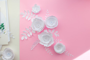Handmade paper art and cut white flowers on pink background. Backstage. 