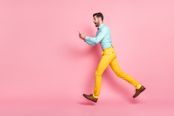 Fototapeta na wymiar Full length body size profile side view of his he nice attractive cheerful bearded glad guy gentleman jumping running using digital device app 5g discount isolated pink pastel color background