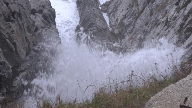 Mountain river rushes noisily among rocks from above to bottom, cold spray flying around. Beauty and power of indomitable natural elemental force in inaccessible corners of planet, extreme travel.