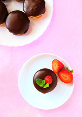 Chocolate dipped sandwich cookies with strawberries on white plate, top view, flat lay, vertical
