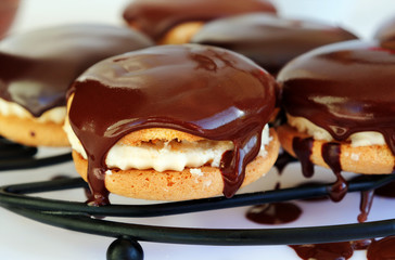 Chocolate covered sandwich cookies with vanilla cream on a wire rack