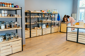 Zero waste shop interior details. Wooden shelves with different food goods and personal hygiene or...