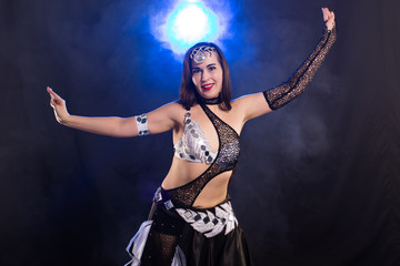 Young woman belly dancer in exotic dress with gold, dancing tribal fusion dance in studio.