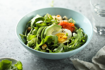 Healthy quinoa bowl with arugula, egg and avocado