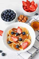 Pancake cereal with honey and berries on white table background