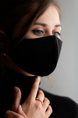 portrait of young beautiful woman in protective black stylish mask with hand with jewelry under her chin, lifestyle 2020 under quarantine and epidemic, fashion disease