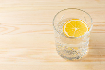 Glass of water with lemon on a wooden table, morning drink for a healthy lifestyle