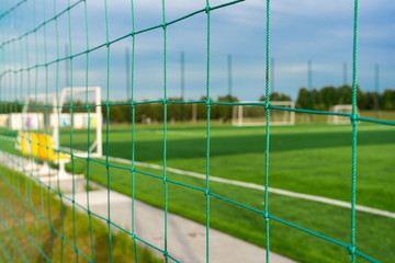 Football goal on the field, view through the fencing net