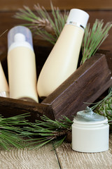 blank bottle packaging with natural cosmetic cream, serum, skincare, lotion, tonic with forest coniferous branches and cones on wooden background. beauty and spa concept. bio organic product.