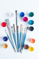 Open jars with gouache and paint brushes of different sizes. The view from the top. Background,...