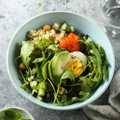 Healthy quinoa bowl with arugula, egg and avocado
