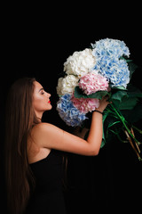 Brunette on a black background with a bouquet of large beautiful flowers