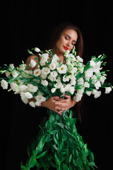 Brunette on a black background with a bouquet of large beautiful flowers
