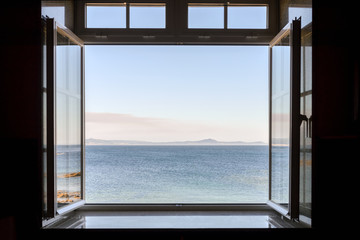view from a dark room to the sea through an open window